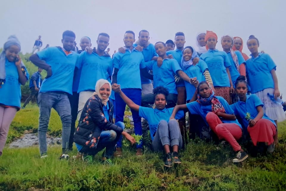 The Colas factory team in matching blue shirts on a green hillside during a Green Legacy planting day.