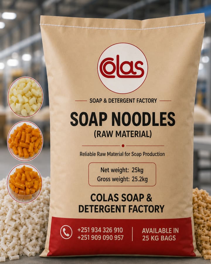A 25 kg Colas Soap & Detergent Factory sack of raw soap noodles, standing between heaps of cream and amber noodles on the factory floor.