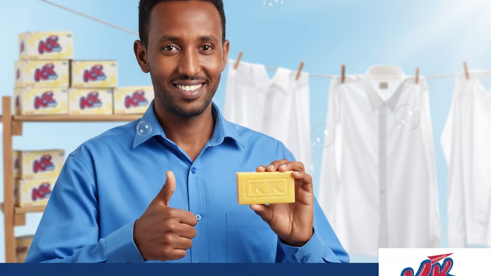 A shopkeeper holding a KK bar in front of shelves stacked with KK cartons.